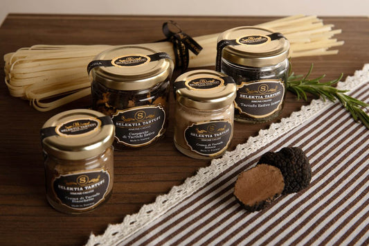 Verschiedene Trüffelcremes und Spezialitäten aus Italien – Pistaziencreme, Pecorino-Trüffelcreme, Carpaccio di Tartufo, Delizia di Funghi und Crema del Tartufaio auf rustikalem Holzbrett, ideal für Pasta, Bruschetta und Gourmetgerichte