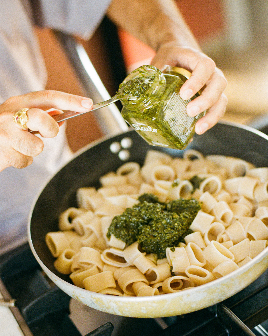 Pesto wird zu italienischer Pasta in einer Pfanne gegeben