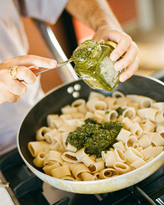 Pesto wird zu italienischer Pasta in einer Pfanne gegeben